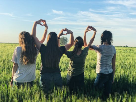 Four teenage girls standing in a field looking over crops